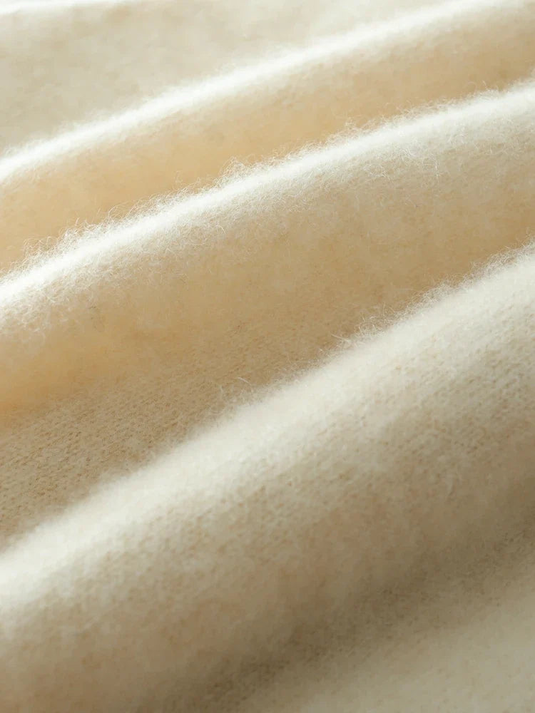 Beige knit sweater fabric close-up with fine knit pattern and soft fuzzy finish