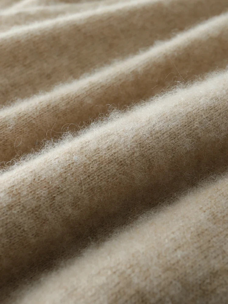 Close-up of beige knit fabric texture with fine fibers and gentle sheen