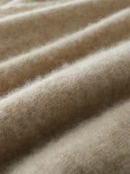 Close-up of beige knit fabric texture with fine fibers and gentle sheen