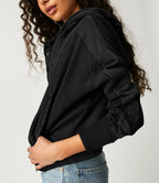 Black waffle knit zip hoodie sleeve and hood detail; textured fabric close view.