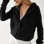 Close-up: black waffle knit zip hoodie with hood, snap buttons, and textured fabric.