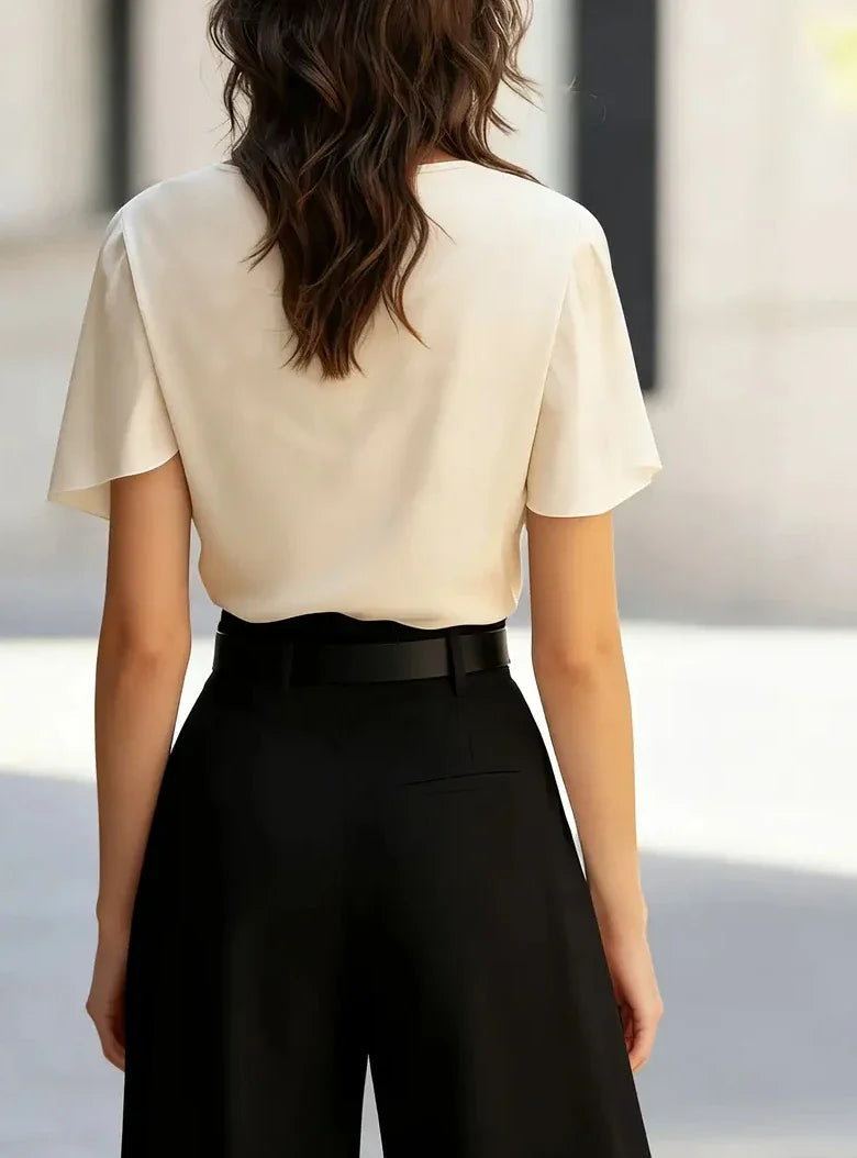 Beige draped cowl-neck blouse from back with short sleeves.