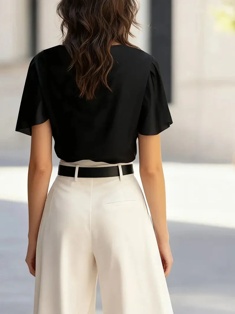 Black draped cowl-neck blouse from back with short sleeves.