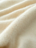 Cream-beige knit sweater fabric close-up showing smooth knit threads and folds