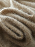 Beige knit sweater fabric close-up with soft fuzzy texture and ribbed detailing