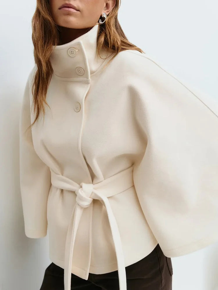 Cream wool-blend cape coat with stand collar, snap buttons, and waist tie belt