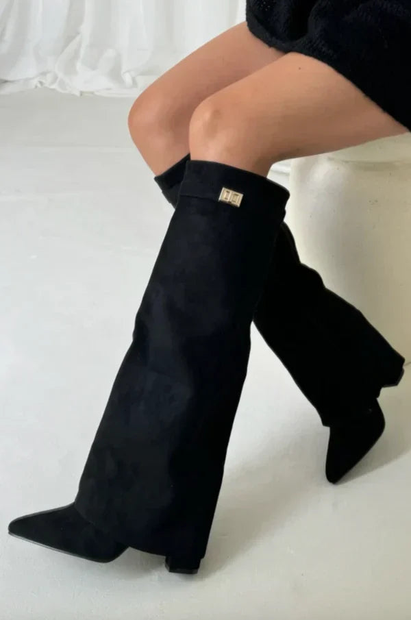 Black suede tall heeled boots with gold buckle; angled view with exposed heel.