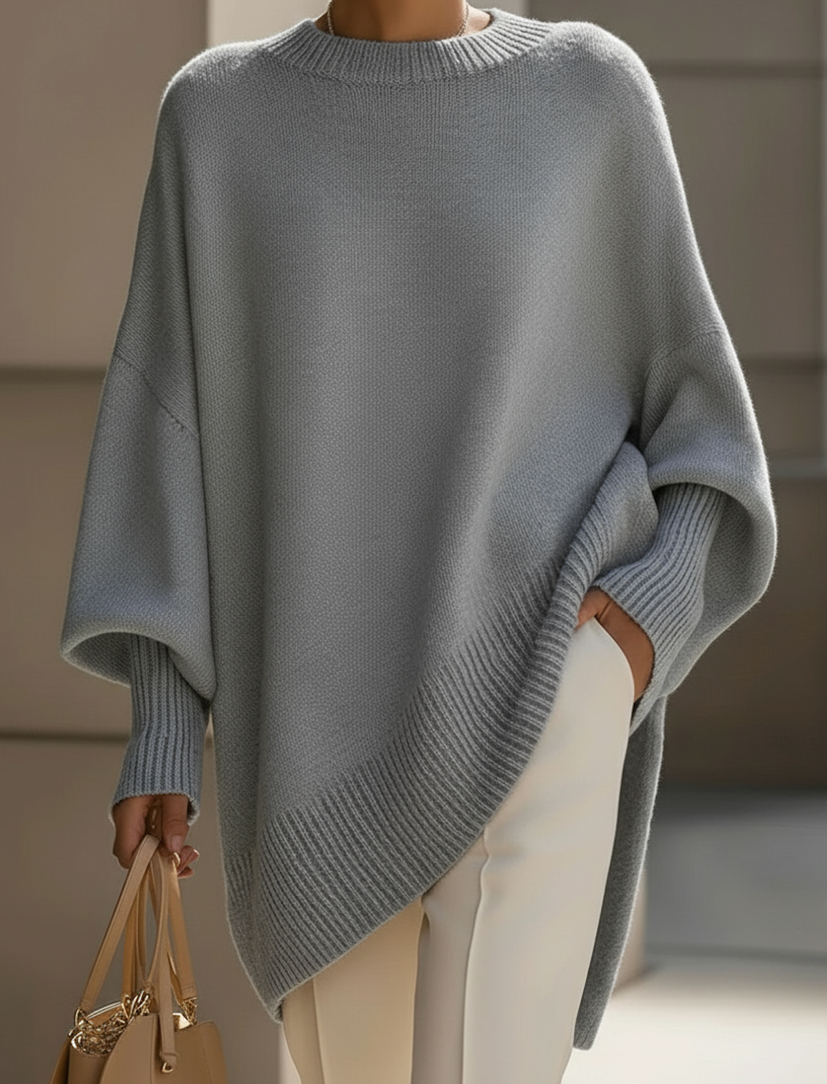 Light gray oversized knit sweater with ribbed crew neck and draped sleeve front