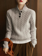 Light gray cable-knit cashmere button-up sweater with black buttons and ribbed hem.