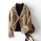Camel and black houndstooth knit jacket on a hanger, button front and lapels.