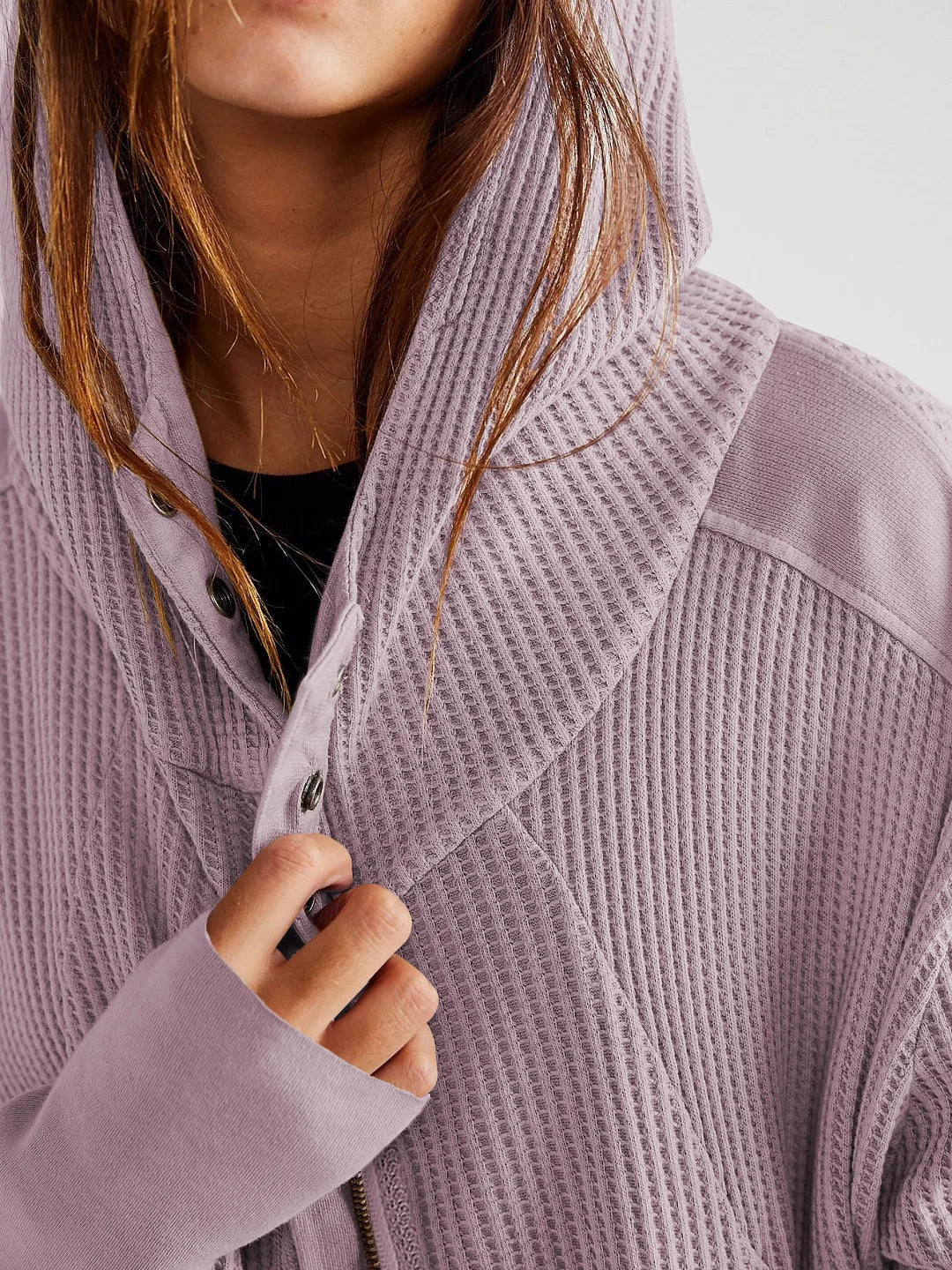 Lavender waffle zip hoodie with hood and button front, close-up with hands.