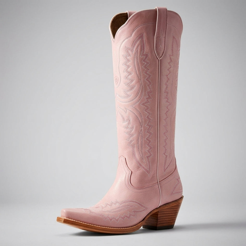 Light pink cowboy boots with embossed western accents, pointed toe, and low block heel