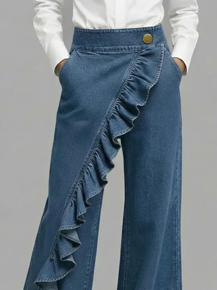 Blue wide-leg jeans with diagonal ruffle overlay and gold button waistband