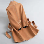 Tan overcoat with wide collar, belt tie at waist, and buttoned cuffs