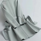 Light gray overcoat with vertical seam, belt at waist, and studded cuff