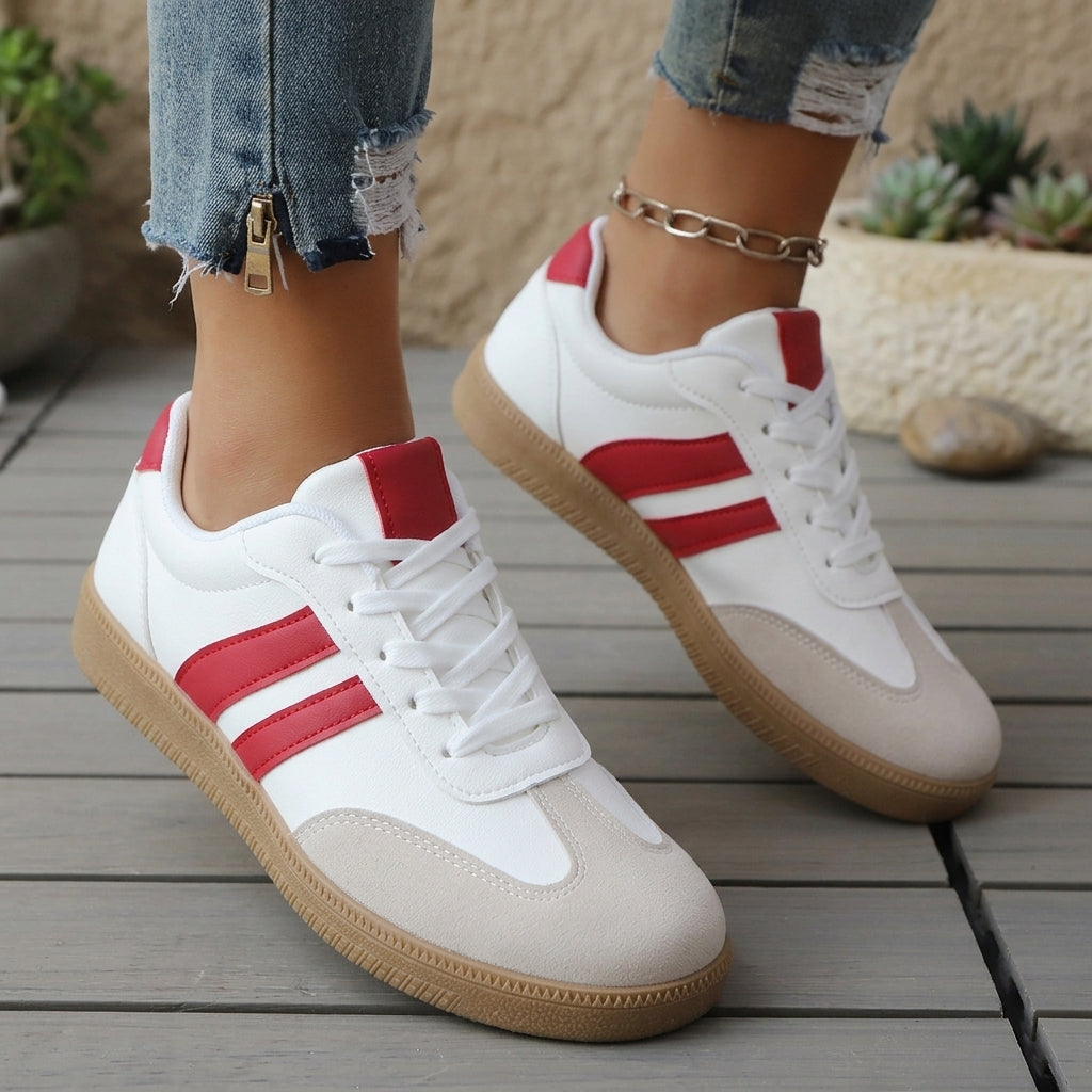Pair of white and red low-top lace-up sneakers with tan gum soles.