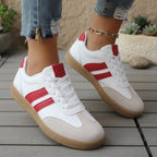 Pair of white and red low-top lace-up sneakers with tan gum soles.