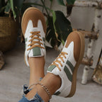 White and green low-top sneaker with tan gum sole and lace-up closure.