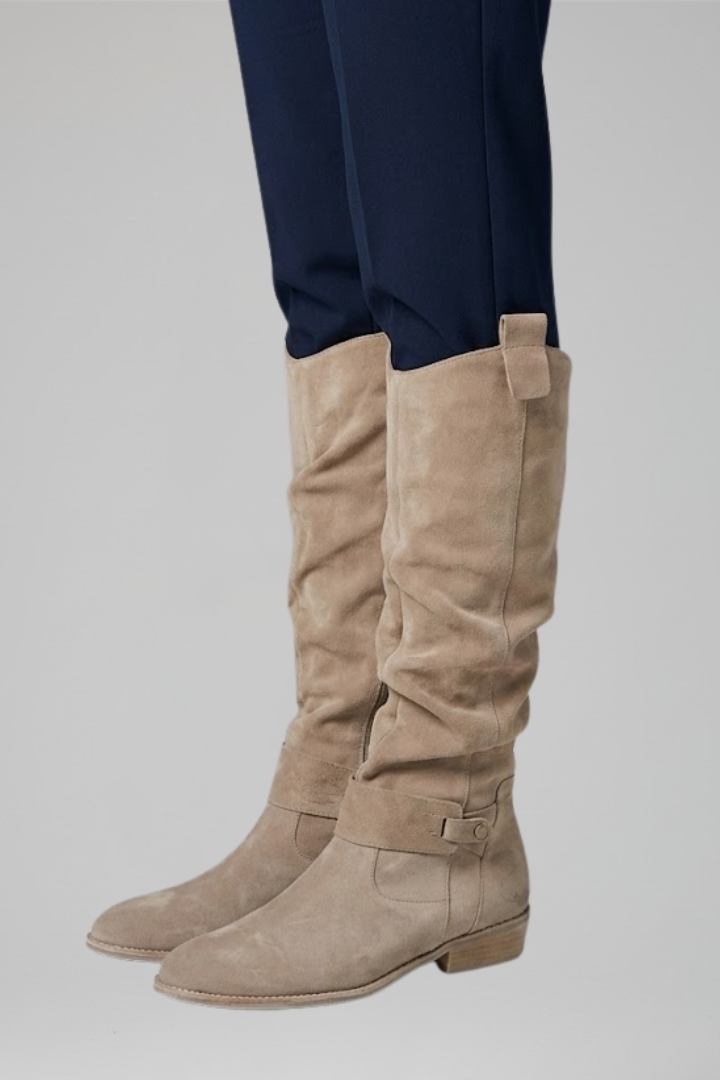Beige knee-high boots with side zipper and buckle ankle strap, low stacked heel.