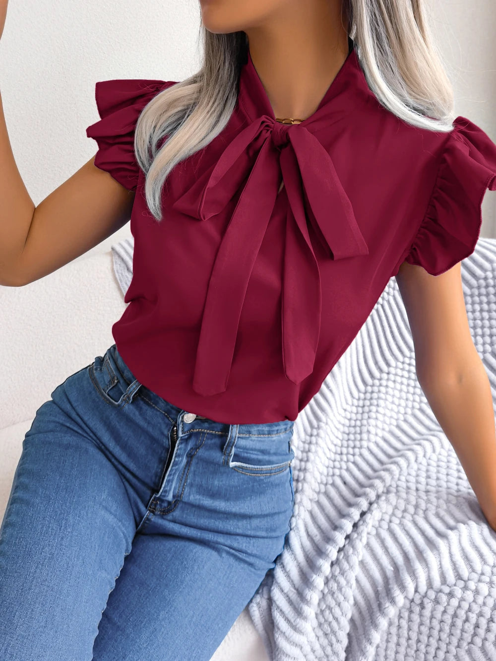Burgundy sleeveless blouse with ruffled cap sleeves and bow tie neckline