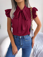 Burgundy sleeveless blouse with bow tie neckline and ruffled shoulder details