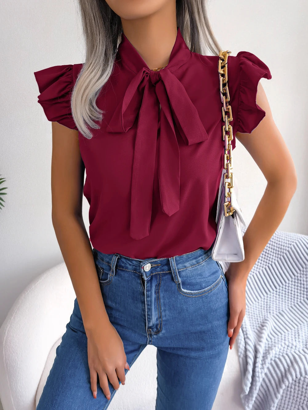 Burgundy sleeveless blouse with bow tie neckline and ruffled shoulder details
