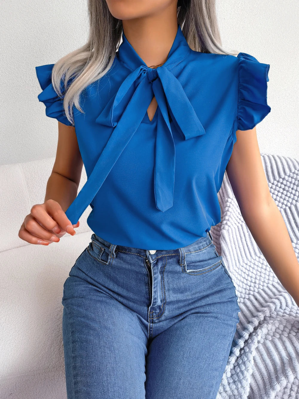 Blue sleeveless blouse with bow tie neckline and flutter ruffle sleeves