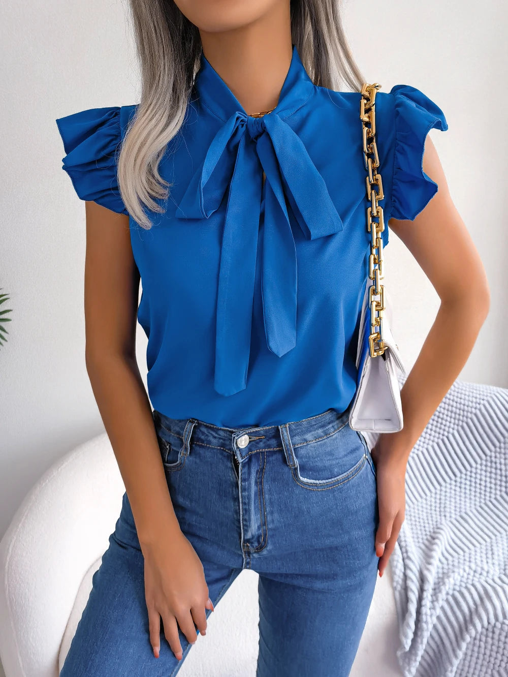 Royal blue sleeveless blouse with bow tie neck and ruffled shoulder accents