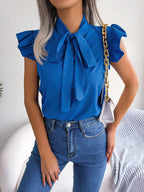 Royal blue sleeveless blouse with bow tie neck and ruffled shoulder accents