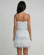 Backless white mini dress with thin spaghetti straps and feather fringe hem