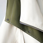 Two-tone trench coat sleeve hem with dark green fabric and metal snap buttons