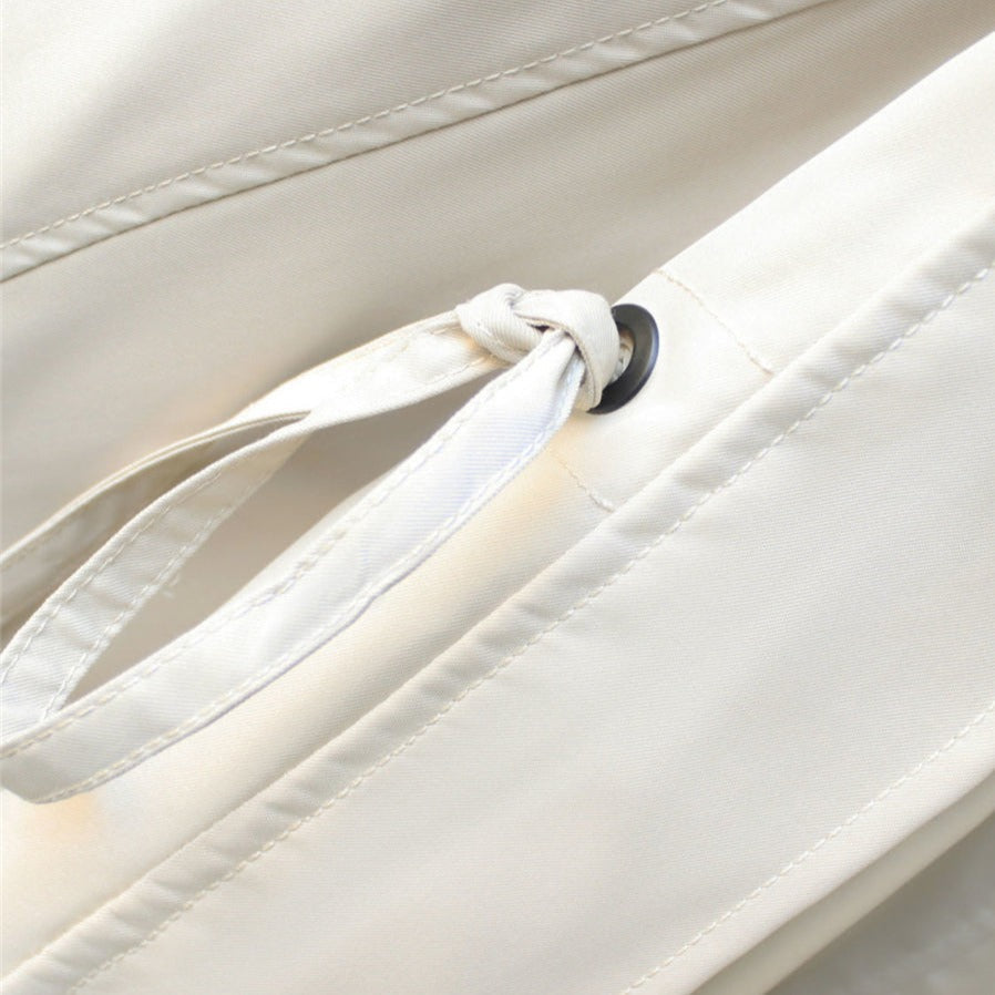 Trench coat drawstring waist detail with tied cord and round black grommet