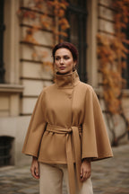 Women's high-collar cape coat in tan, side view with belt tie and buttoned collar