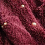 Burgundy shearling coat front with three pearl snap buttons, textured pile