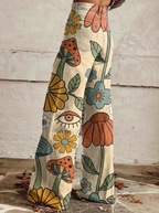 Retro floral wide-leg jeans in cream with large eye, flower, and leaf graphic print.