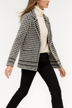 White and black houndstooth knit jacket, three-quarter side view with hem border.