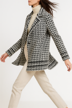 White and black houndstooth knit jacket with notch lapels and ribbed cuffs.